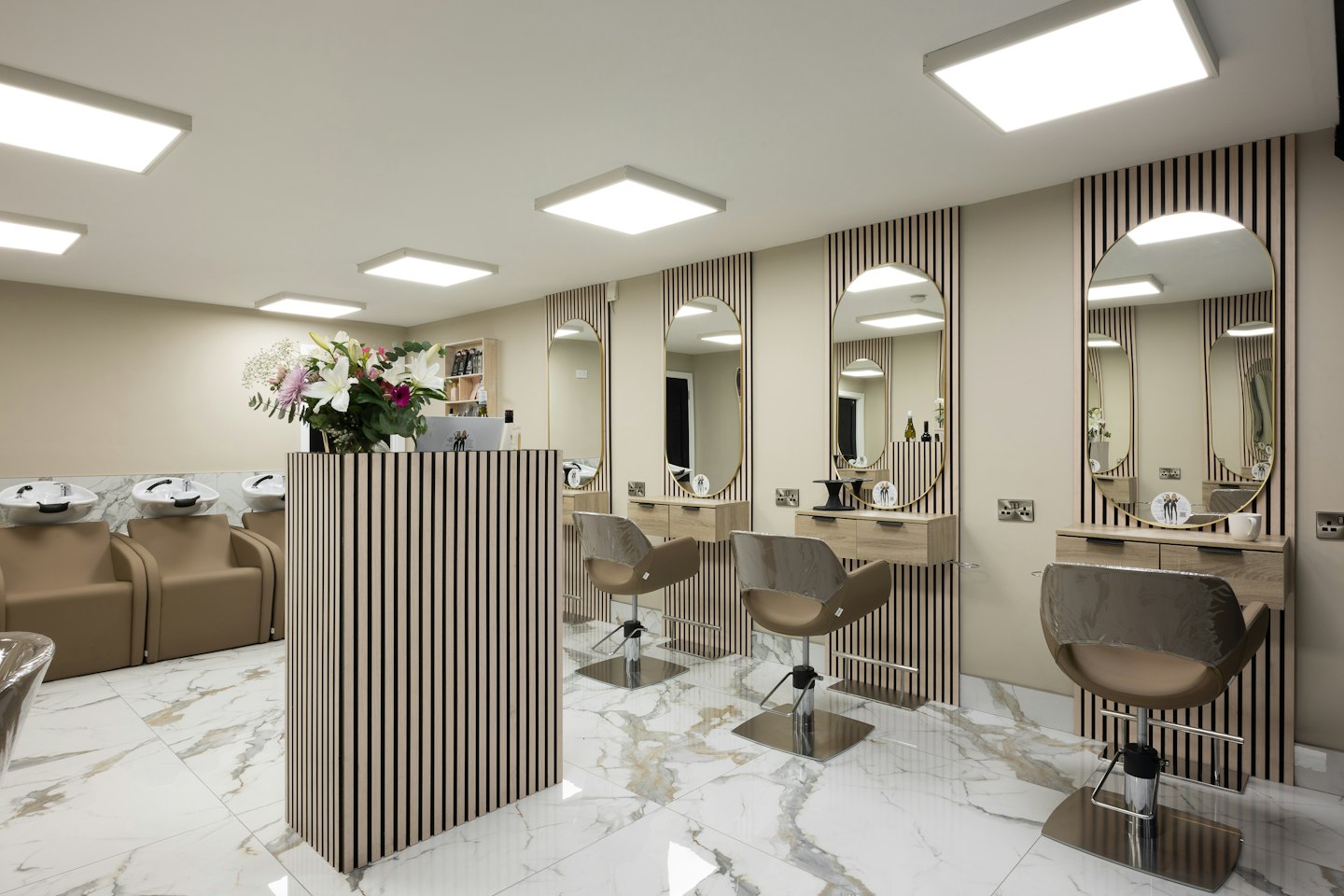 Moderner Friseursalon mit Friseurstühlen und Waschbereich.