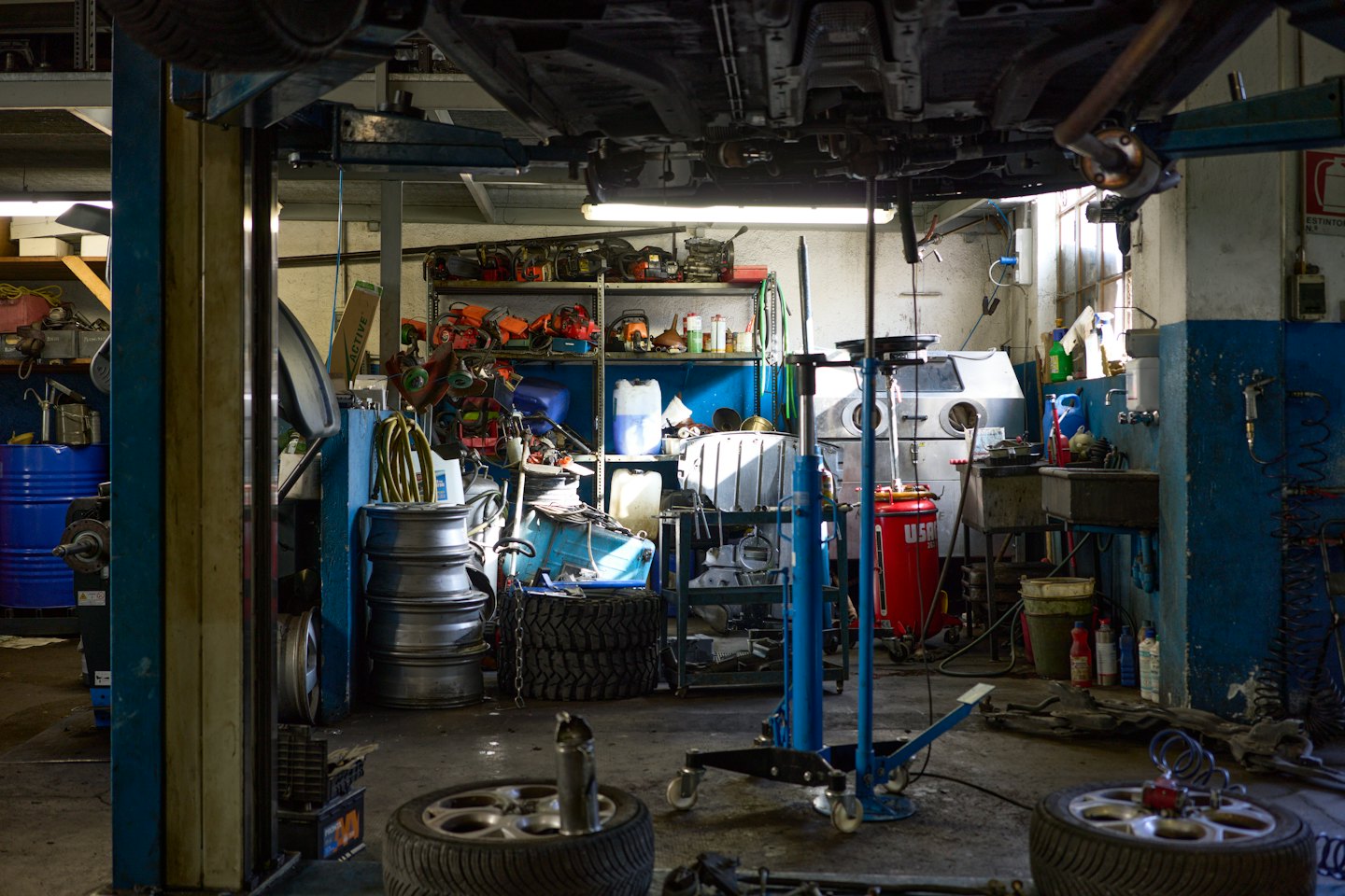 Auto in einer belebten Werkstatt auf einer Hebebühne.
