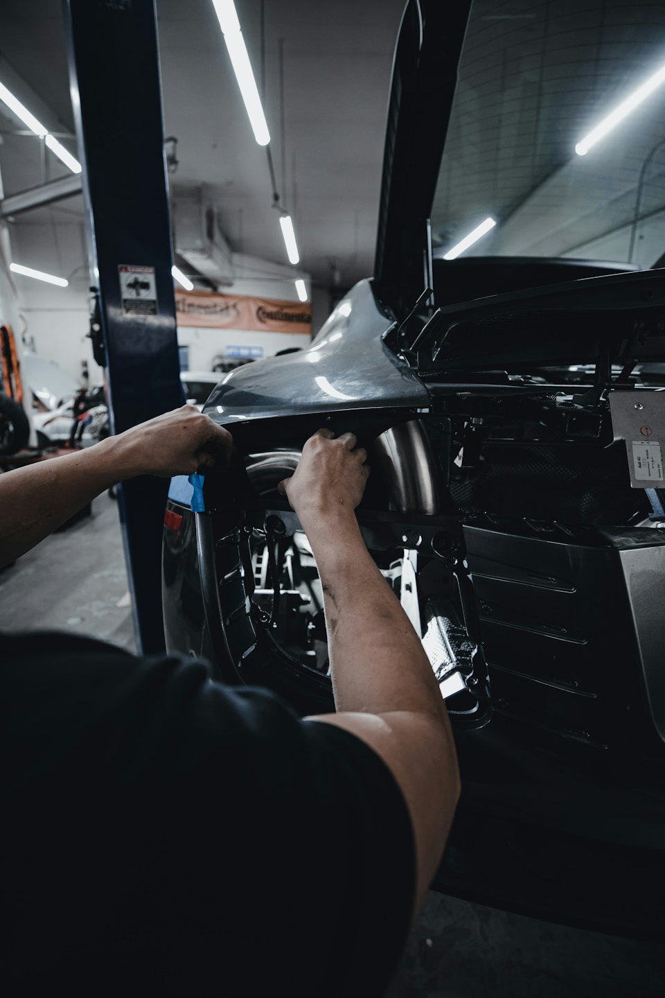 Mechanikerhände arbeiten an der Heckverkleidung eines Autos.
