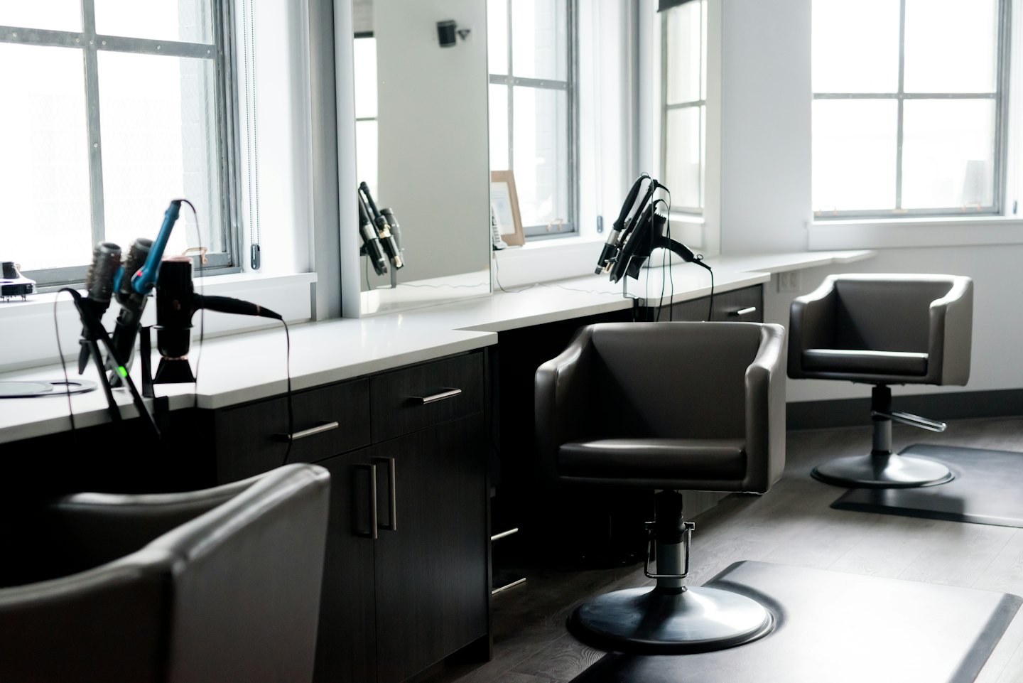Leere Friseurstühle mit Styling-Werkzeugen und Spiegeln.